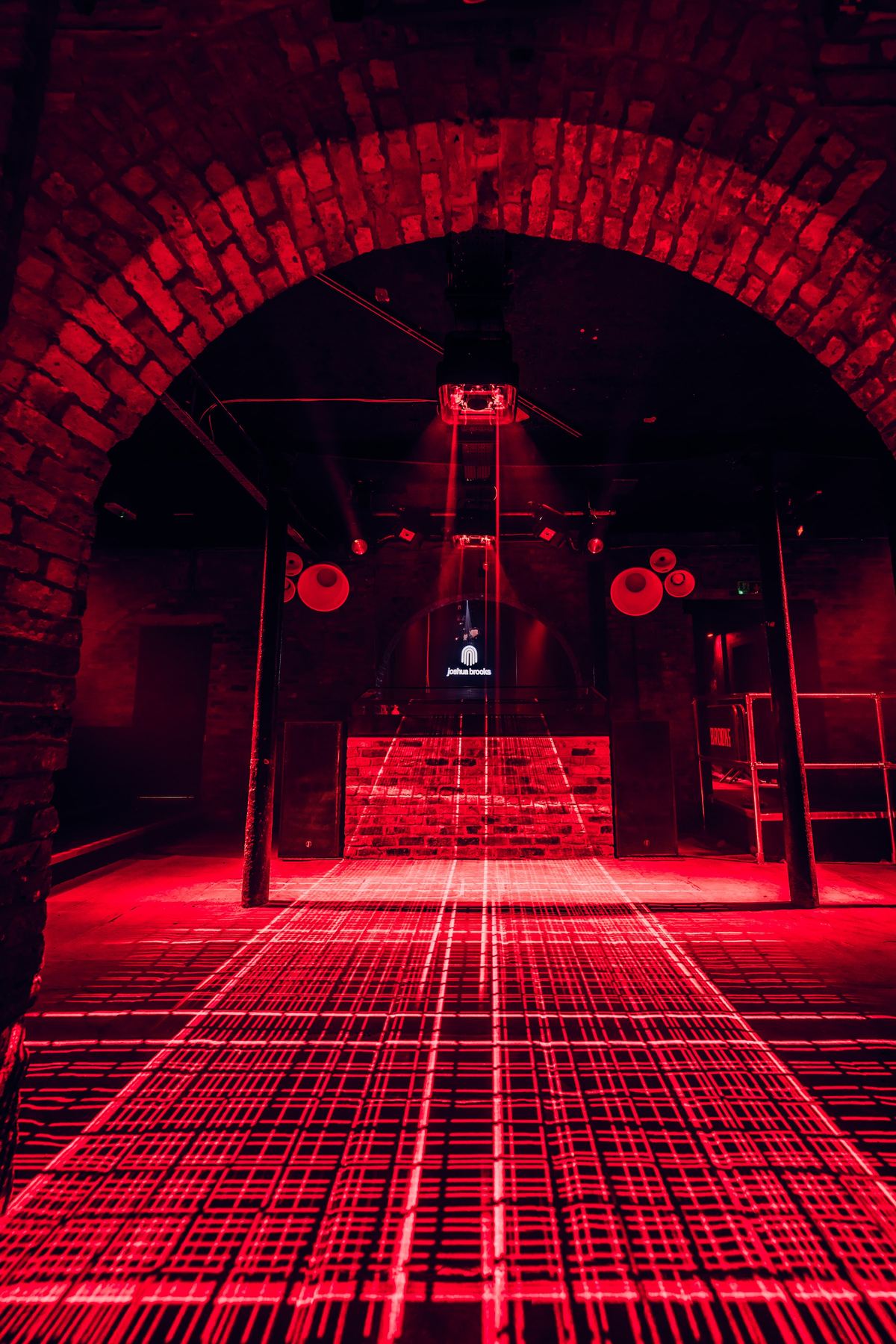 the dj booth framed by the brick arch in red light